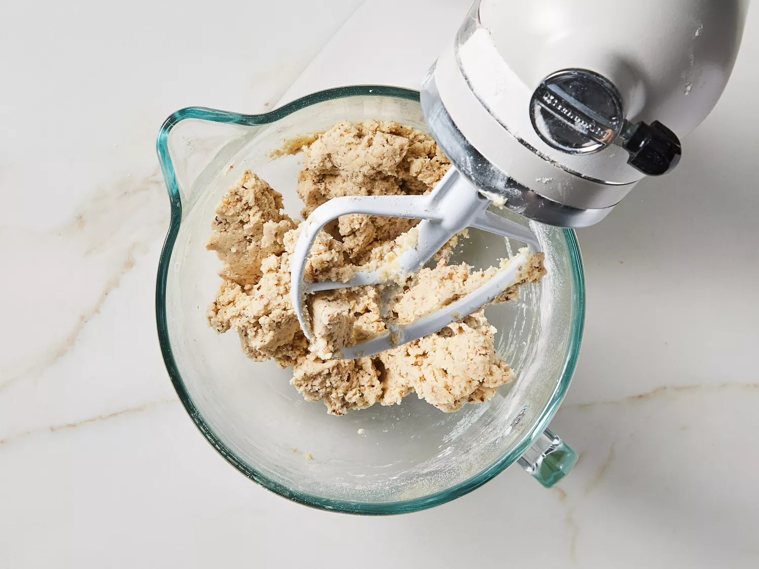 A stand mixer with cookie dough in the mixing bowl