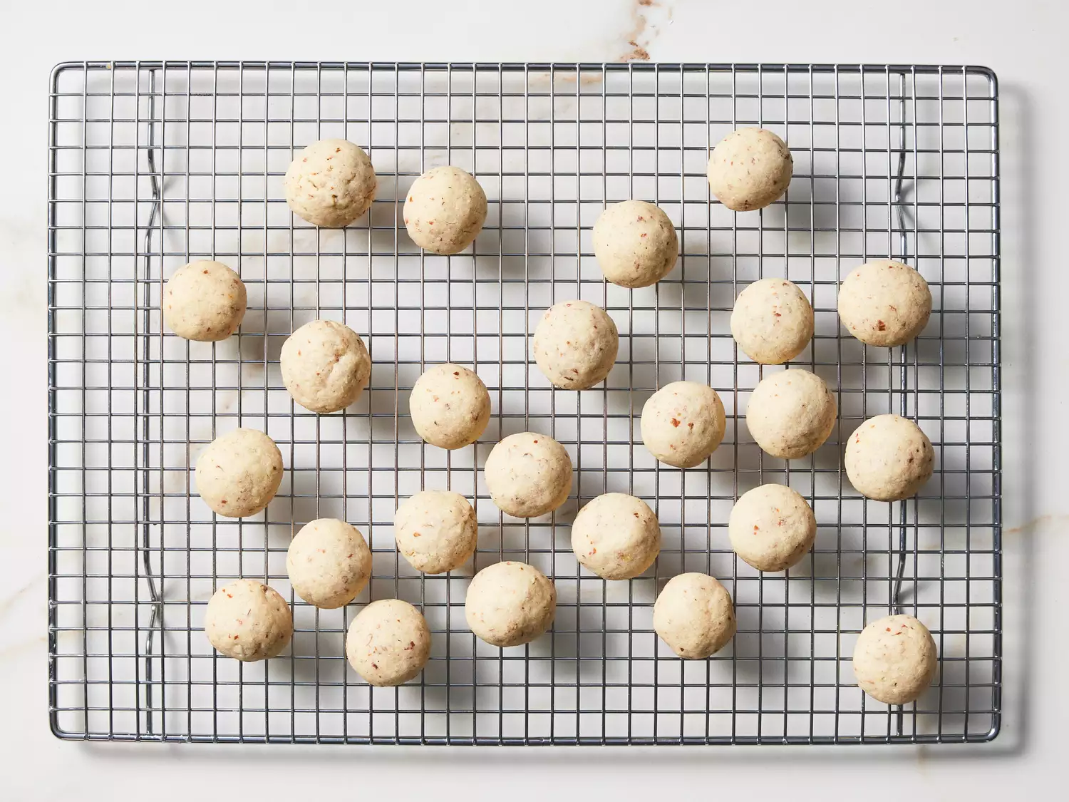 A wire rack with Mexican wedding cookies