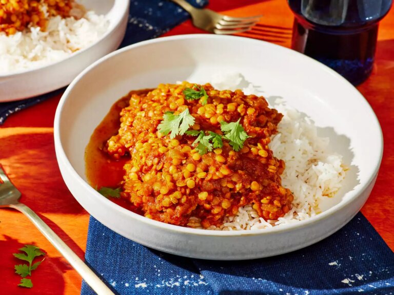 A bowl of red lentil curry, served with white rice and garnished with fresh cilantro