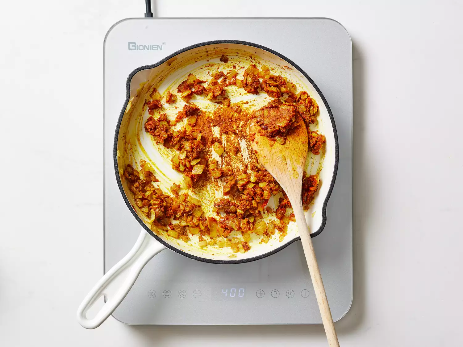 A pan of caramelized onions with curry paste, curry powder, turmeric, cumin, chili powder, salt, sugar, garlic, and ginger