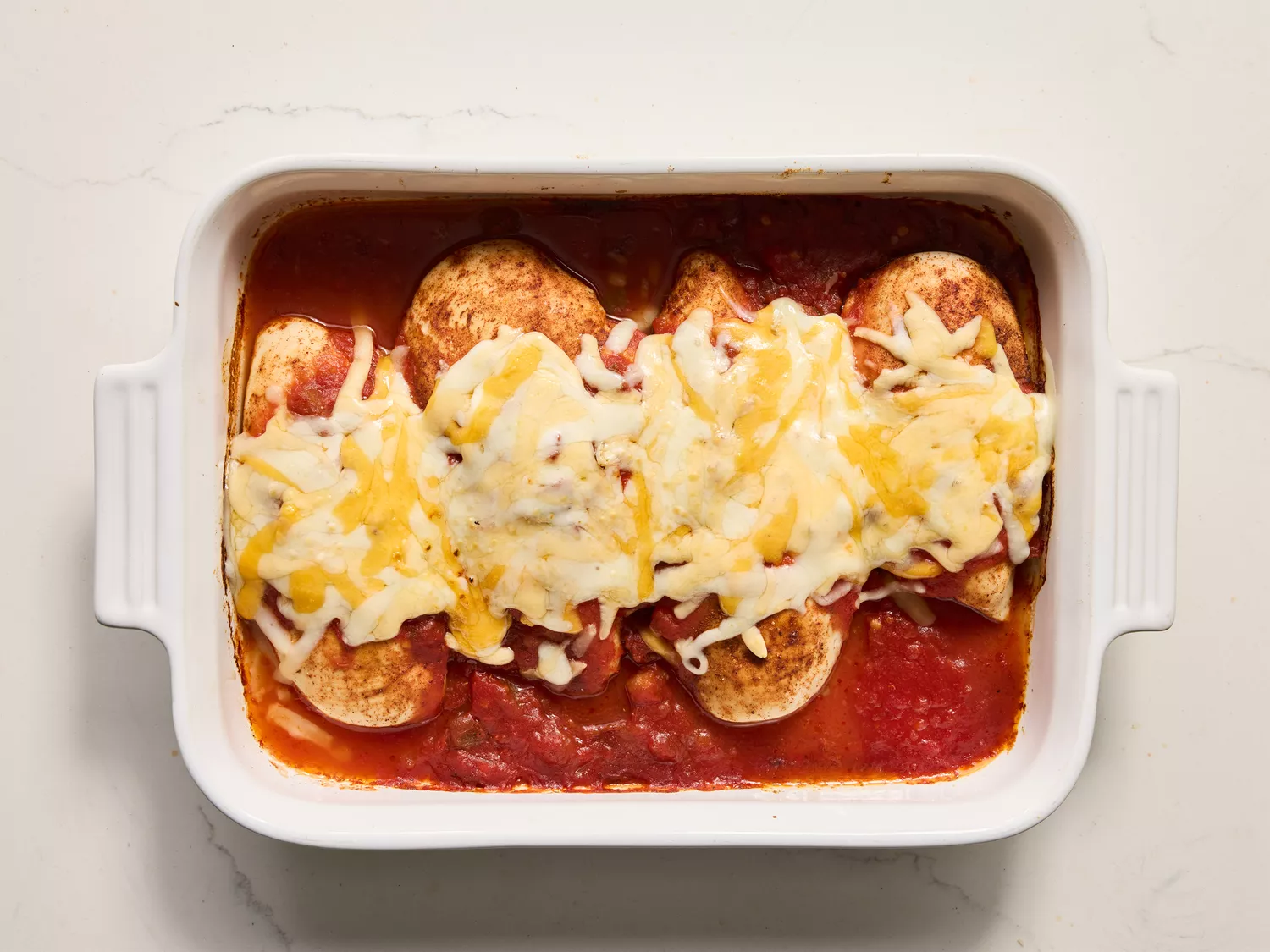 A baking dish of salsa chicken topped with melted cheese