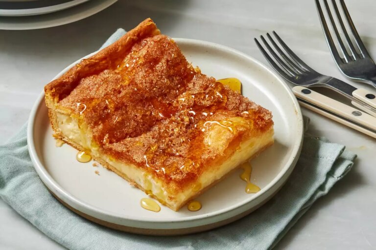 A plated slice of sopapilla cheesecake pie, drizzled with honey
