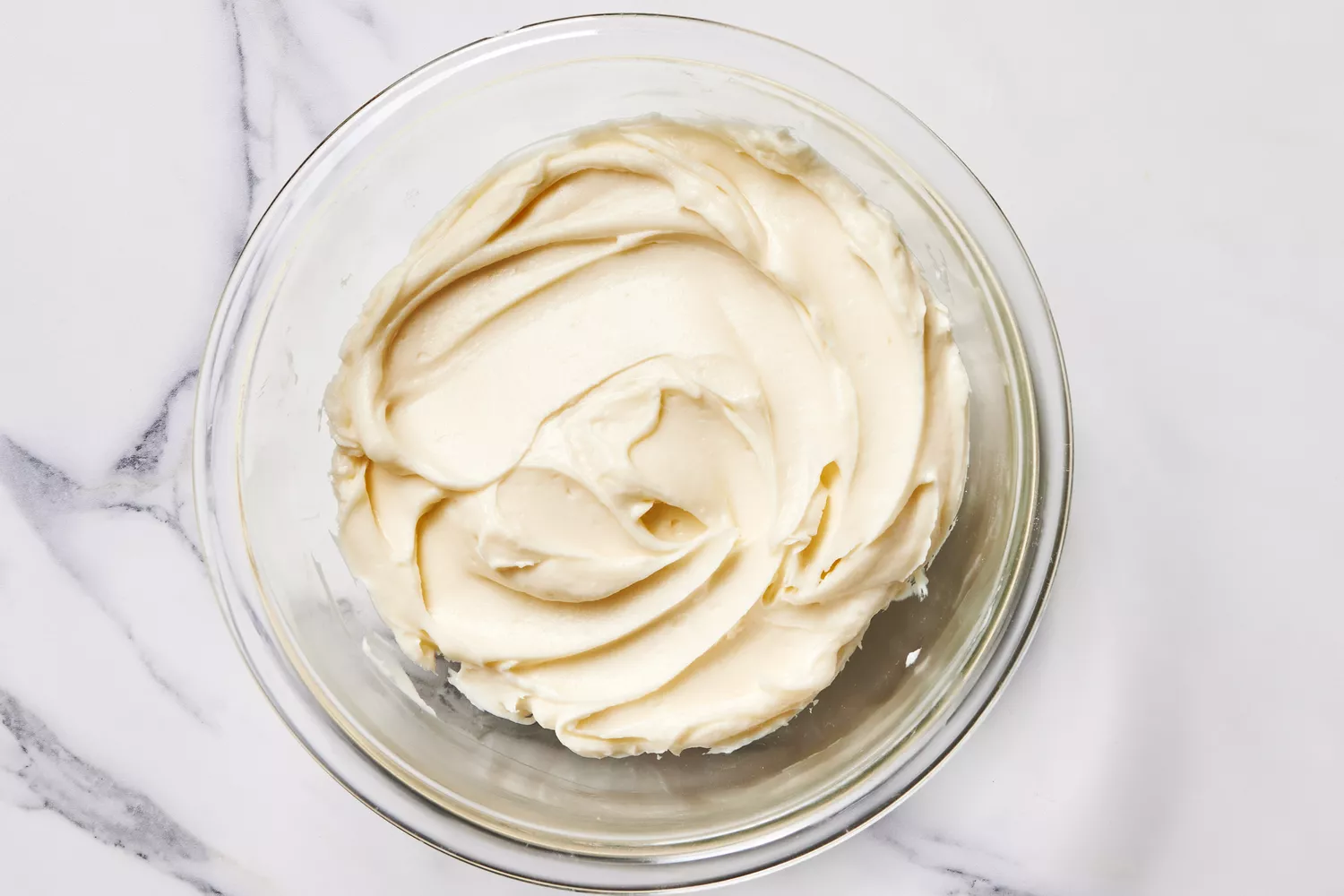 A bowl of cream cheese mixed with sugar and vanilla extract