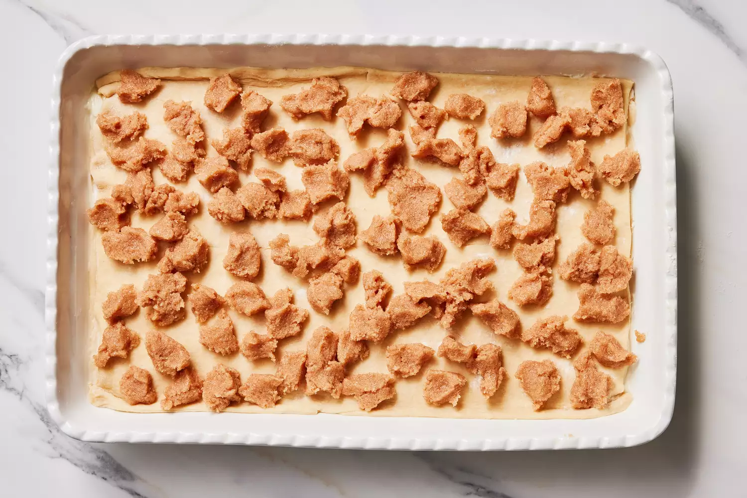 A baking dish with crescent dough dotted with buttery cinnamon sugar mixture