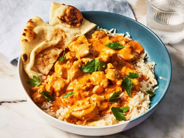 A bowl of slow cooker butter chicken, served over rice with naan