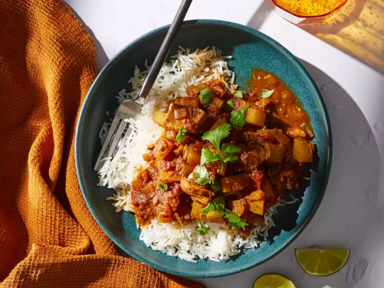 A bowl of chicken vindaloo served over jasmine rice and topped with cilantro