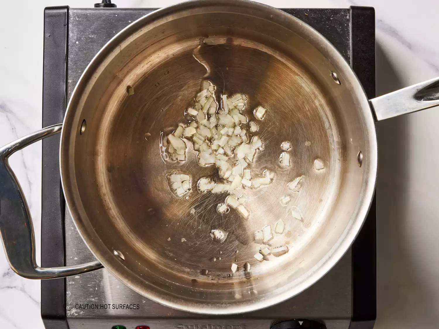 A pan with chopped onion cooking in vegetable oil