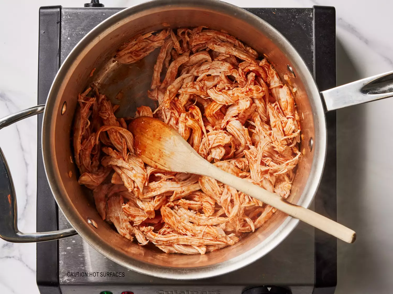 A pan with seasoned, shredded chicken taco filling