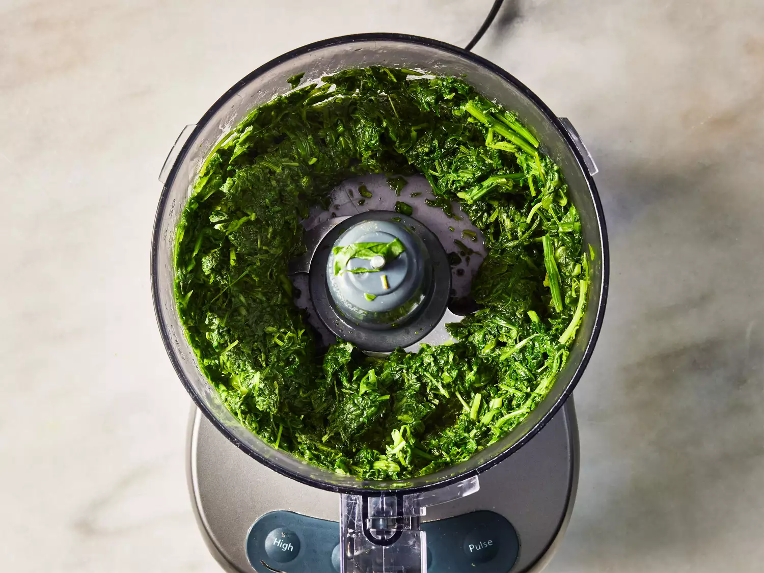A food processor with coarsely chopped spinach