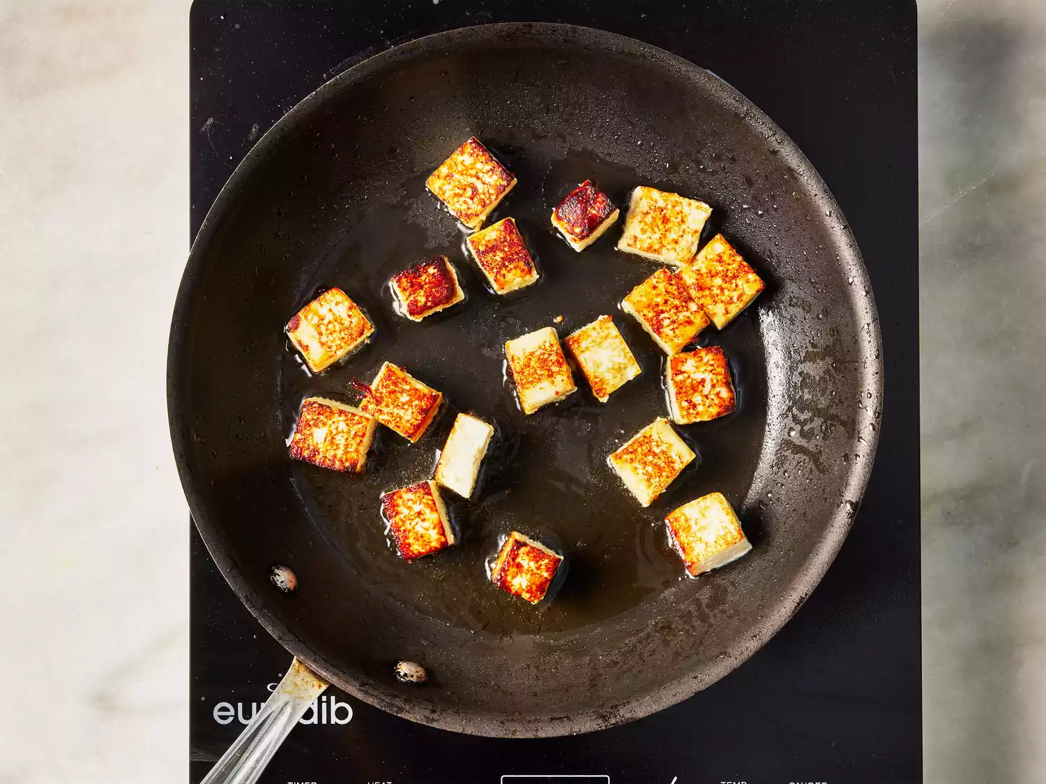 A pan with browned cubes of paneer