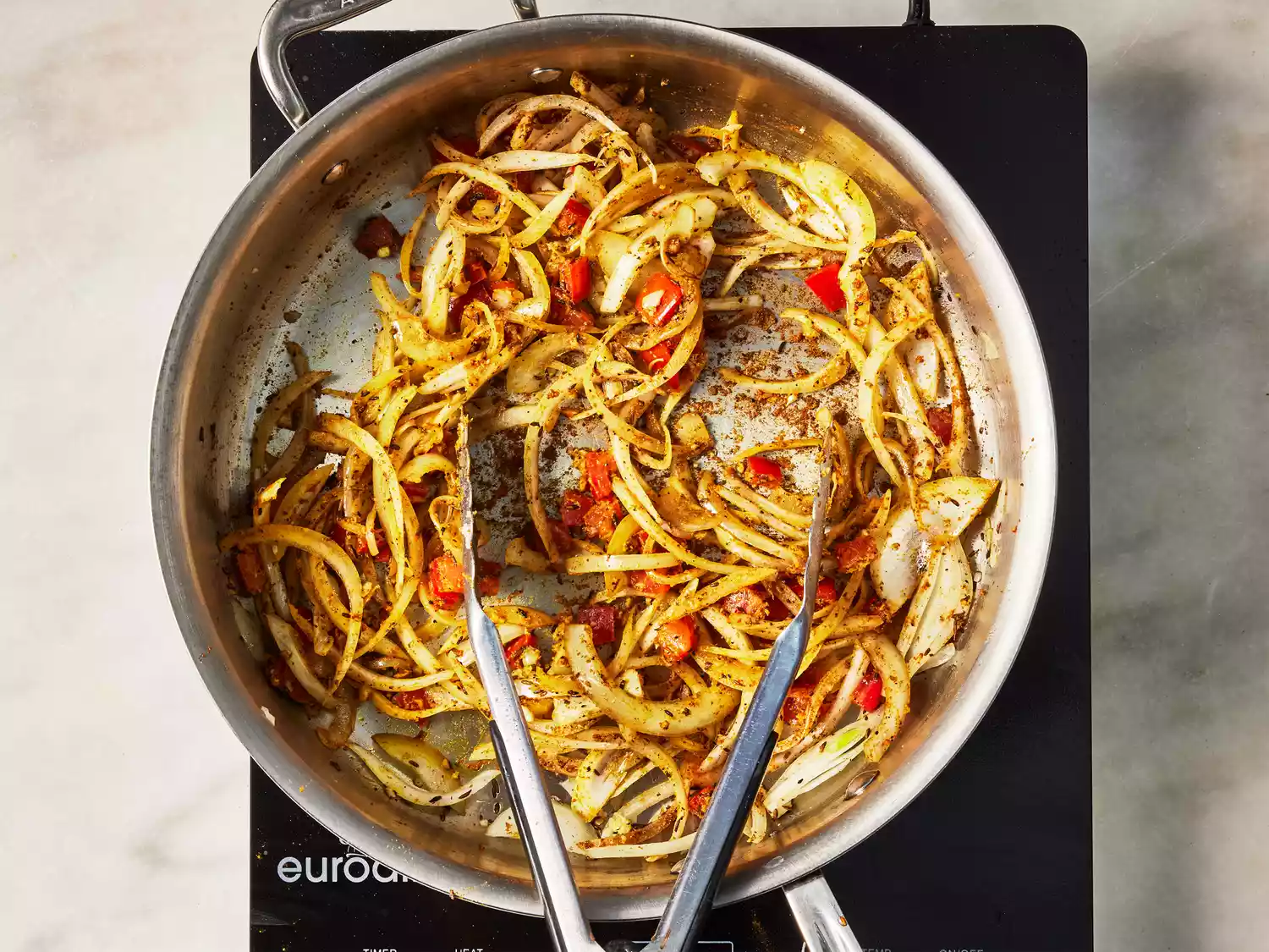 A pan of sliced onions and tomatoes, cooking down in spices