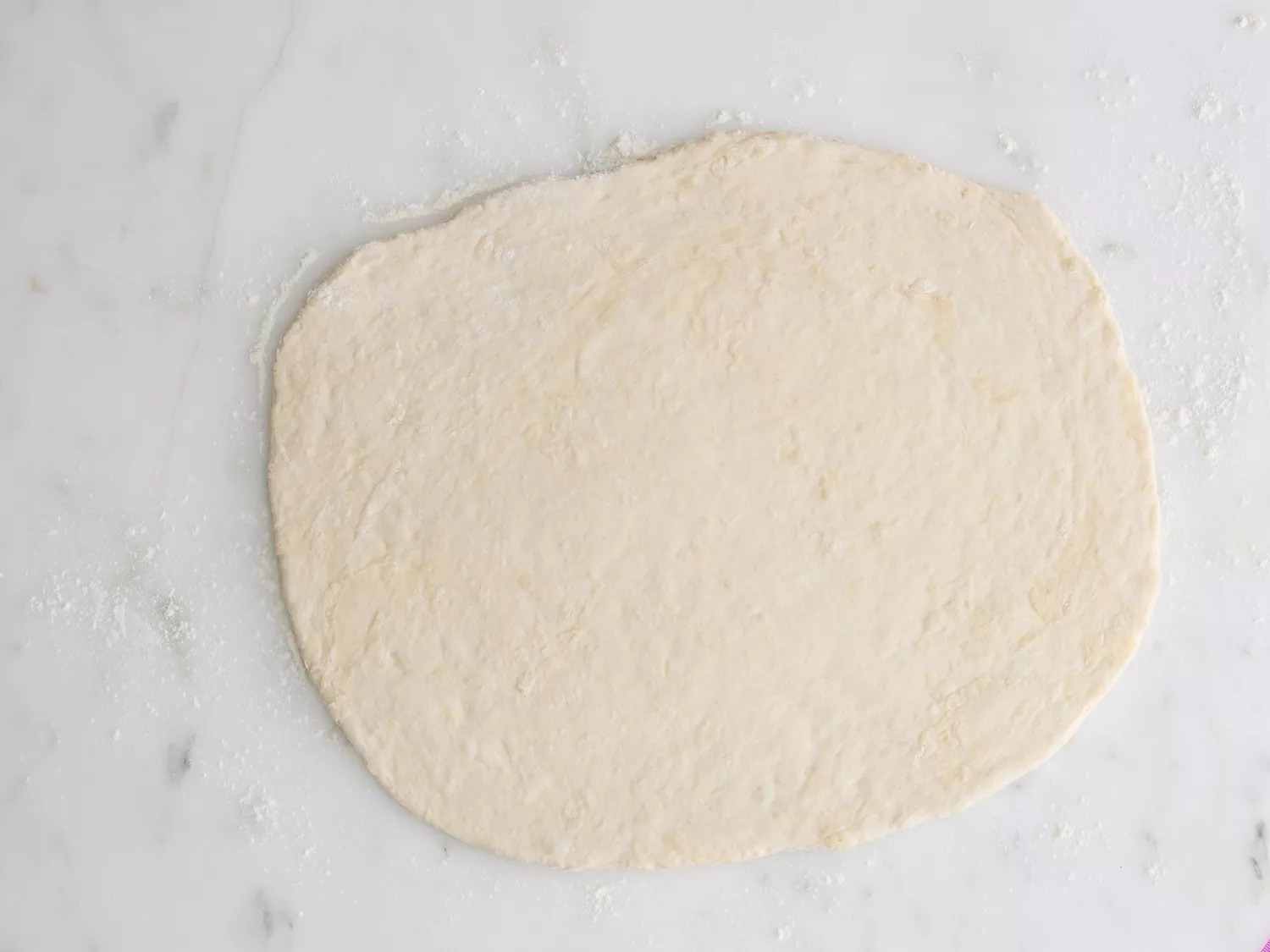 A flat, rolled out piece of dough on a floured surface