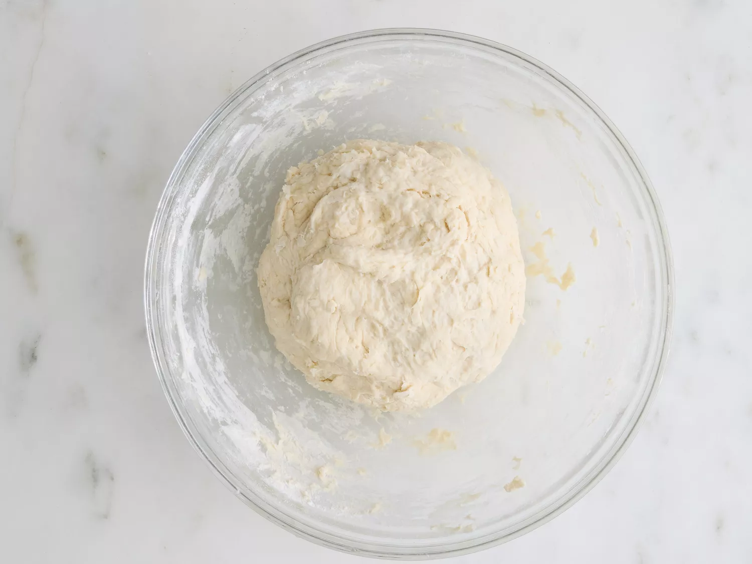 A glass bowl with a ball of smooth sopapillas dough