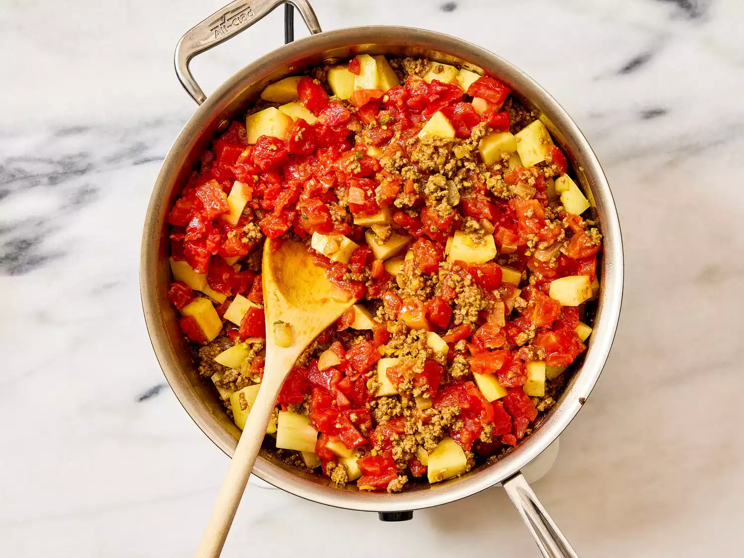 A pan of cooked ground beef with chopped tomatoes and potatoes