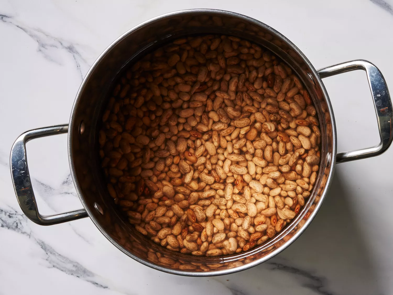 A large pot with dried pinto beans in water