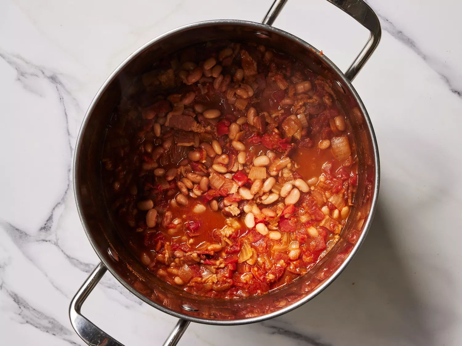 A large pot of simmered pinto beans with bacon and seasonings