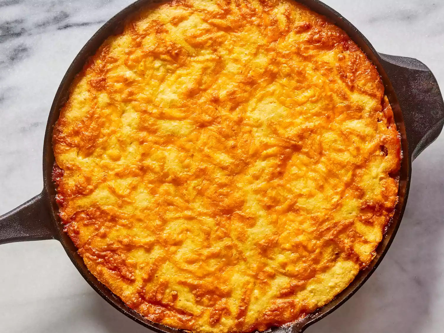 A baked tamale casserole topped with melted shredded cheese