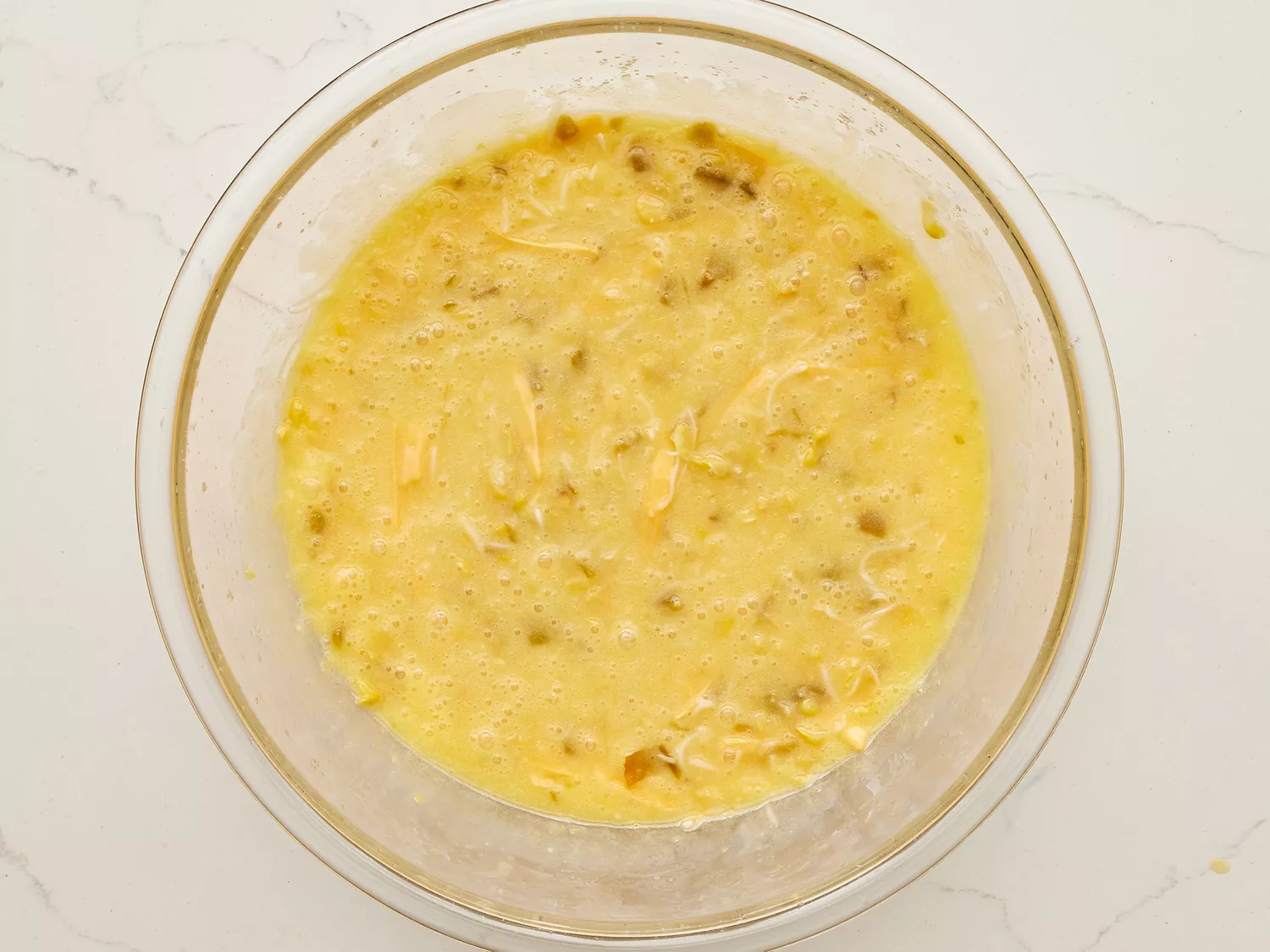 A bowl with butter, sugar, eggs, corn, chiles, and shredded cheese
