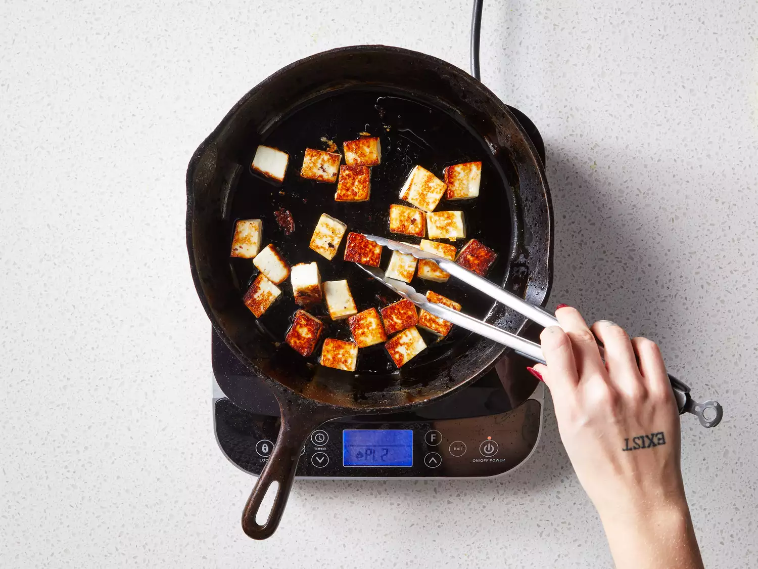 A skillet with browned cubes of paneer cheese