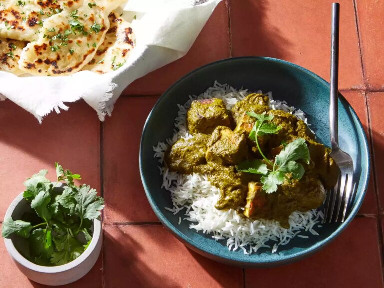 A bowl of palak paneer served over jasmine rice, topped with cilantro