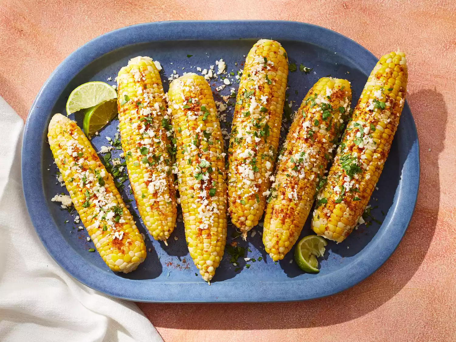 A platter of mexican street corn, served with lime wedges