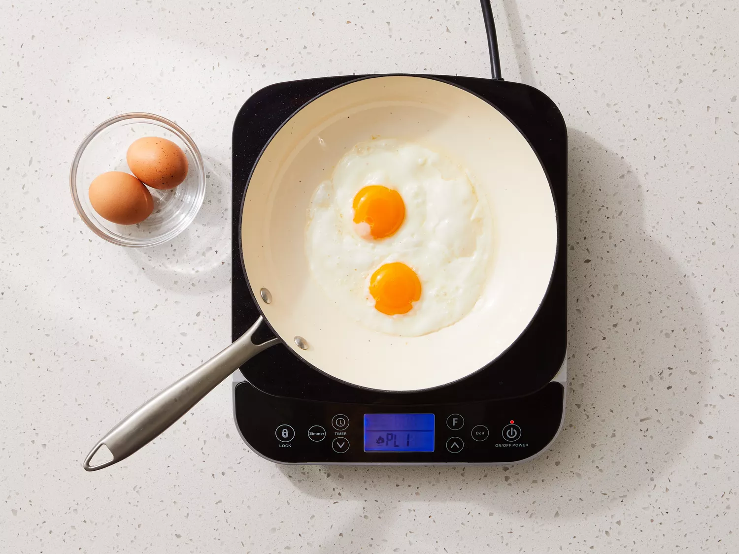 A skillet with two fried eggs with raw yolks