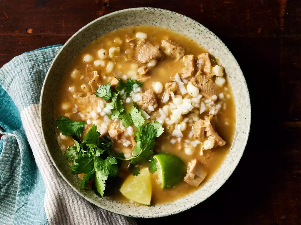 A bowl of menudo rojo served with lime and cilantro