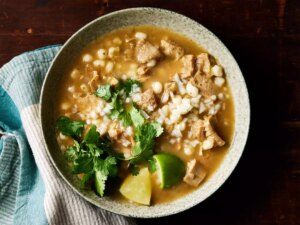 A bowl of menudo rojo served with lime and cilantro