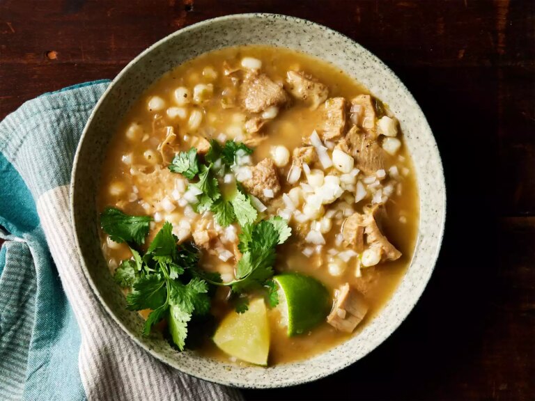 A bowl of menudo rojo served with lime and cilantro