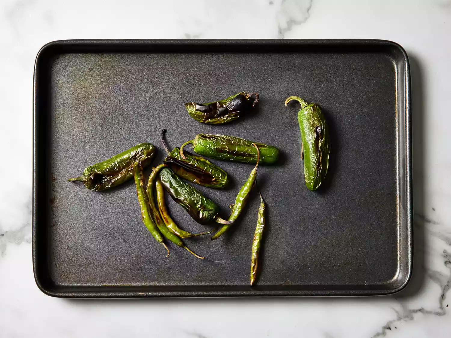 A baking sheet with scorched chile de arbols 