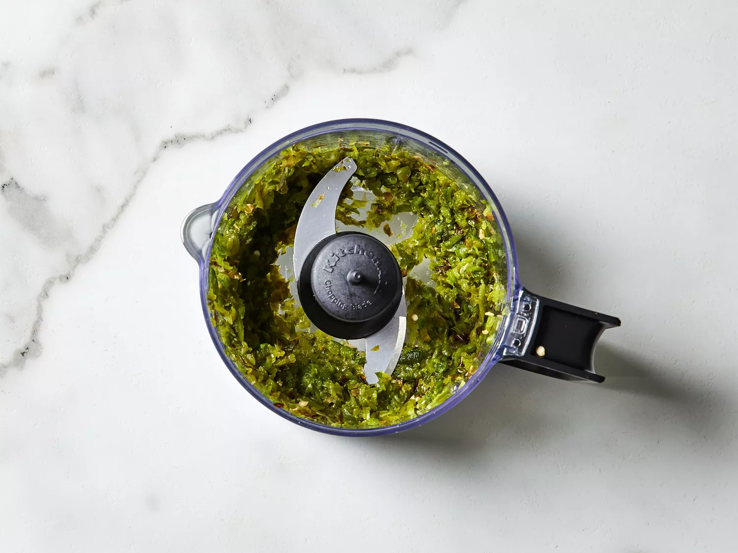 A food processor with minced chile de arbols and japones chiles