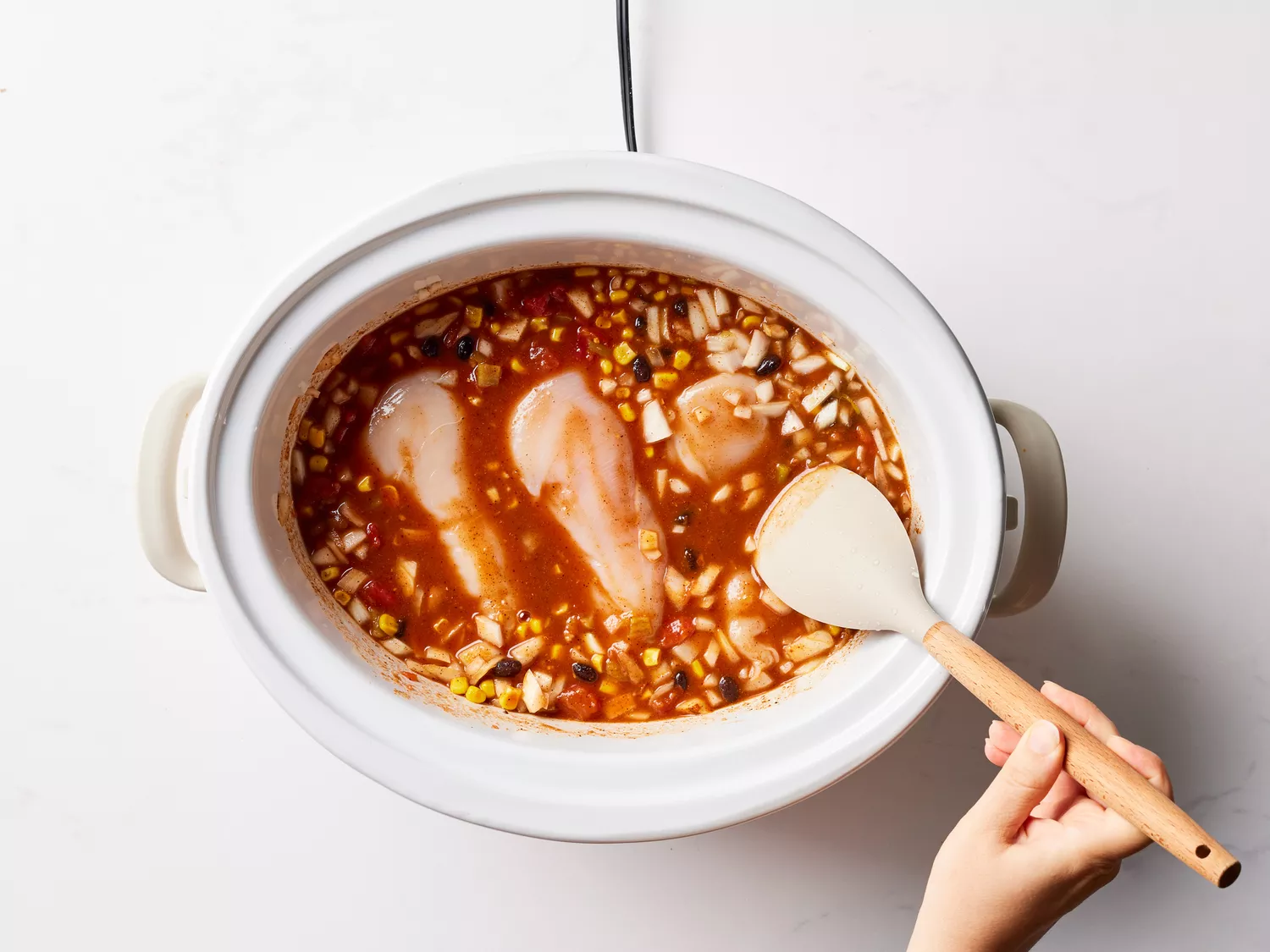 A slow cooker with chicken breasts and bean-tomato mixture
