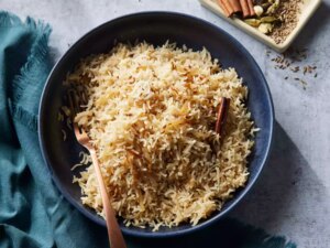 A bowl of indian style basmati rice with a small dish of spices