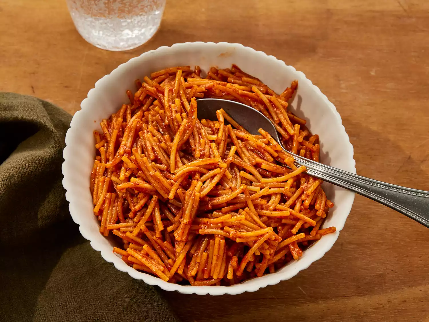 A bowl of fideo served with sparkling water