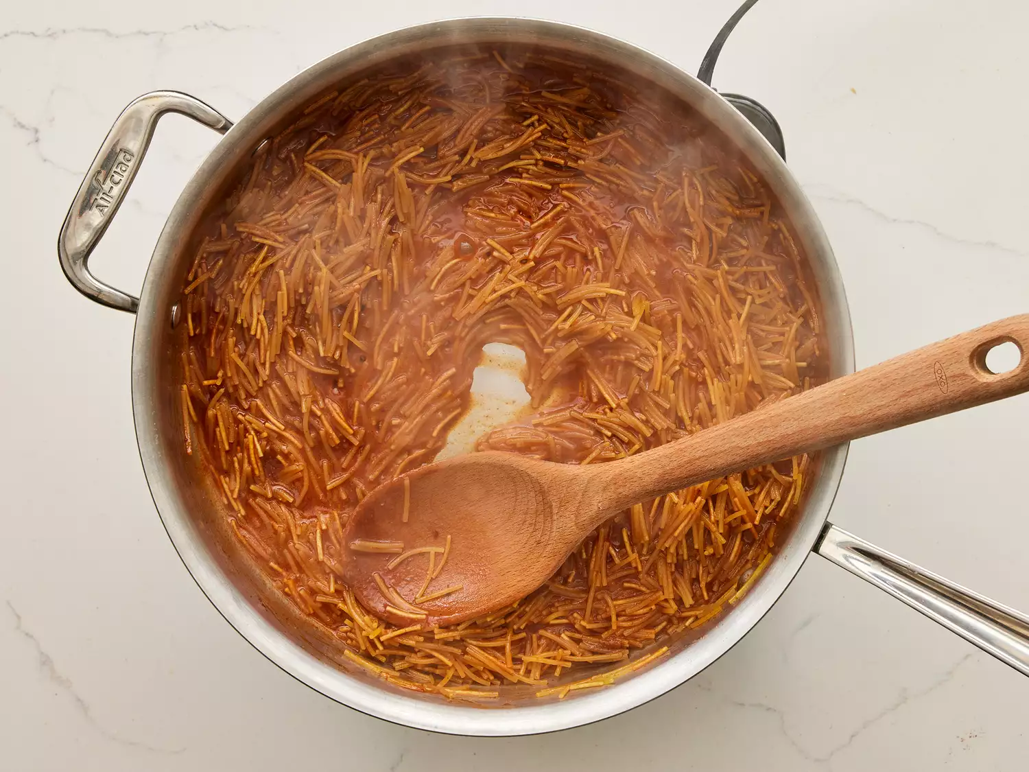 A pot of Fideo in simmering tomato sauce