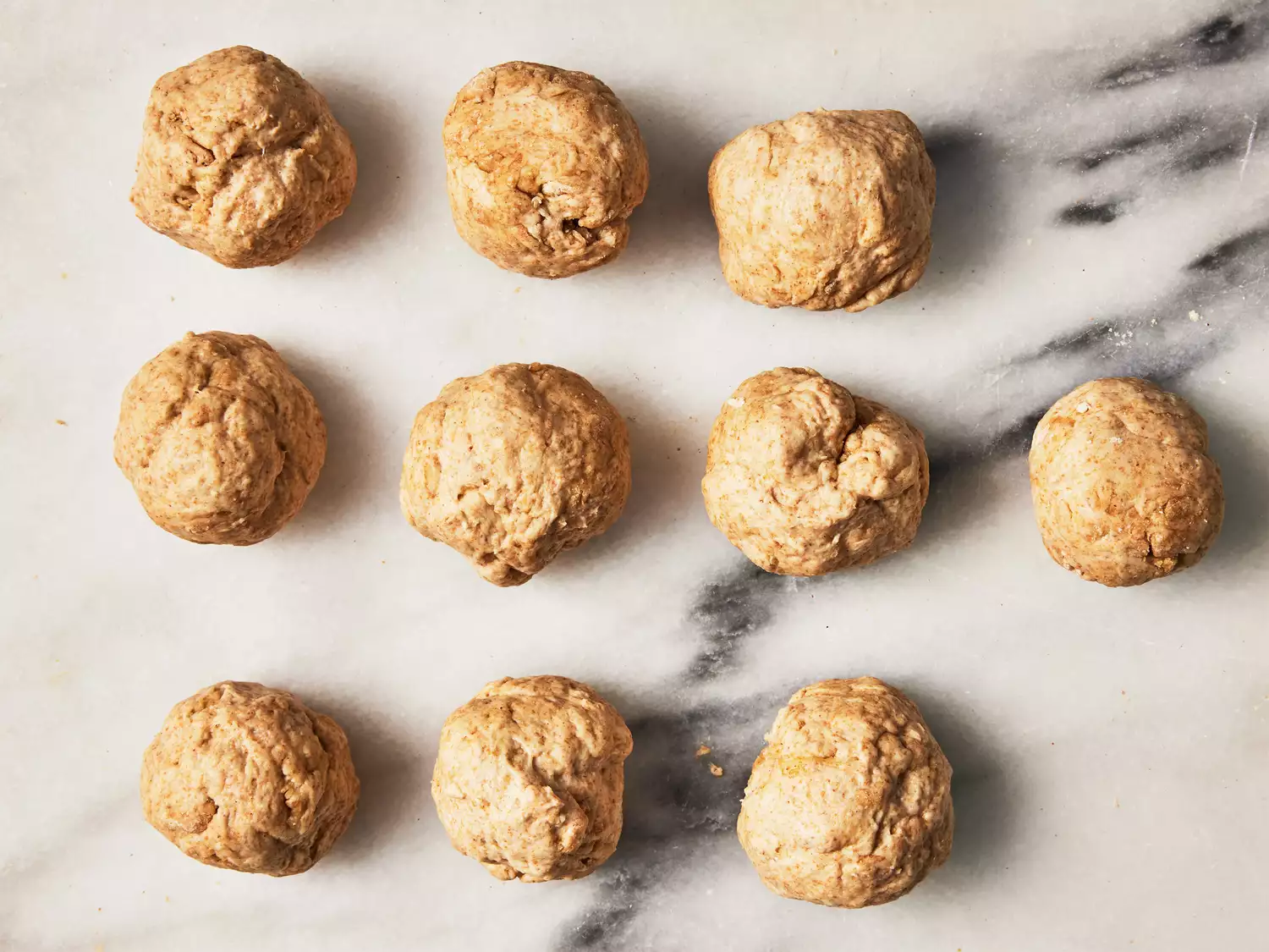 10 small equal balls of dough on a marble surface