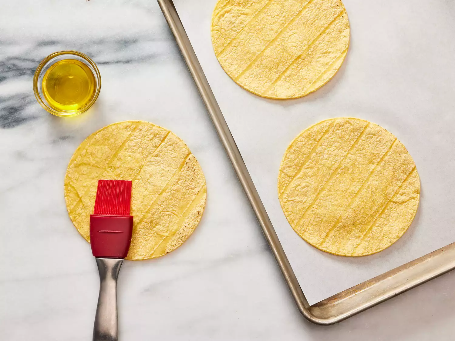 A pastry brush brushing oil onto a tortilla