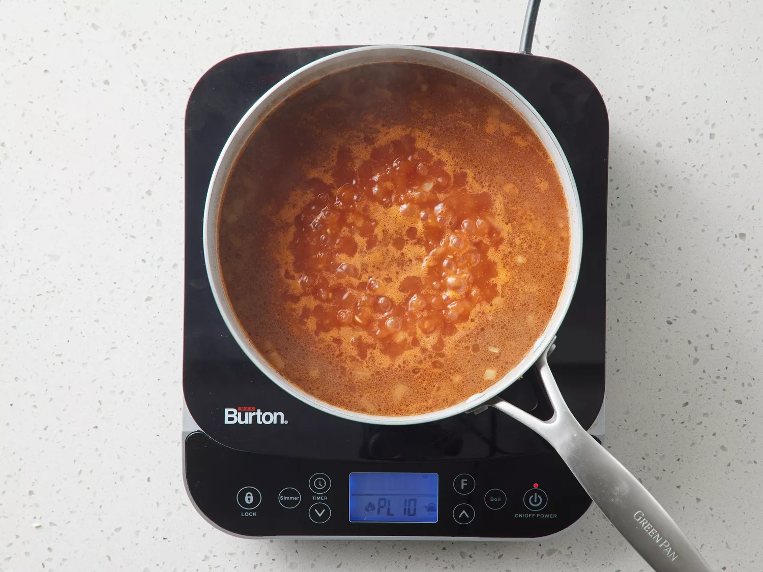A pan with rice cooking in simmering chicken broth and tomato sauce