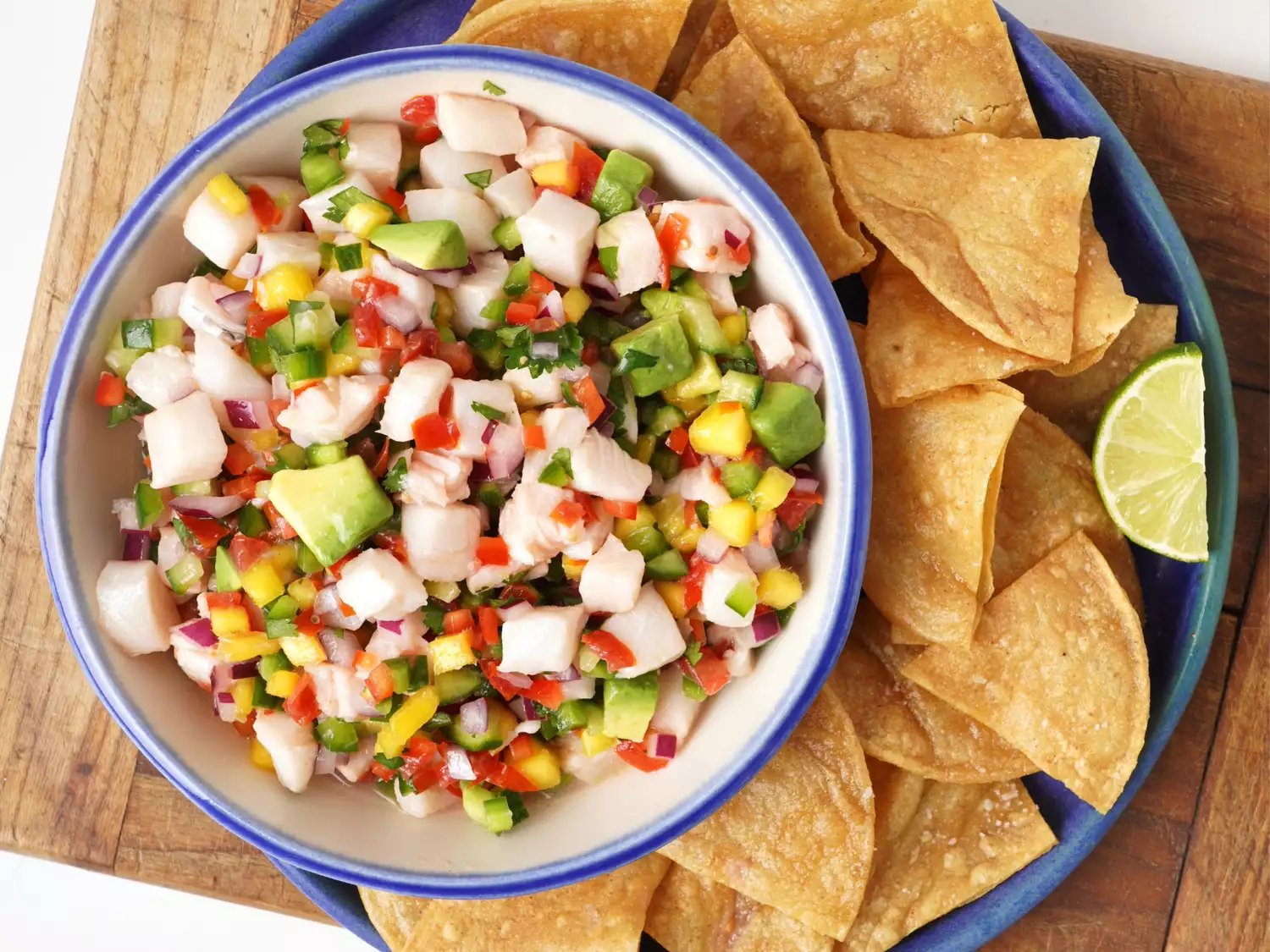 Sea bass ceviche in a shallow bowl with tortilla chips and lime on the side