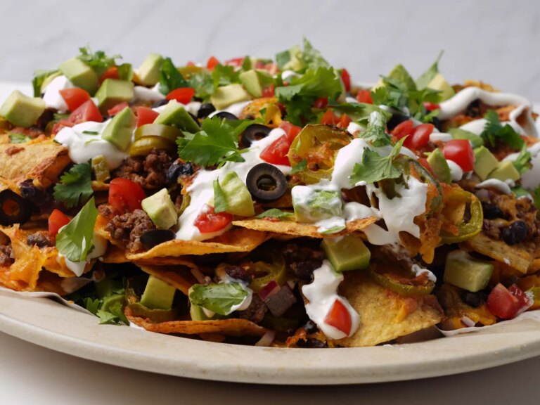 Layered dip with tortilla chips. ground beef, sour cream, tomatoes, jalapenos, and cilantro