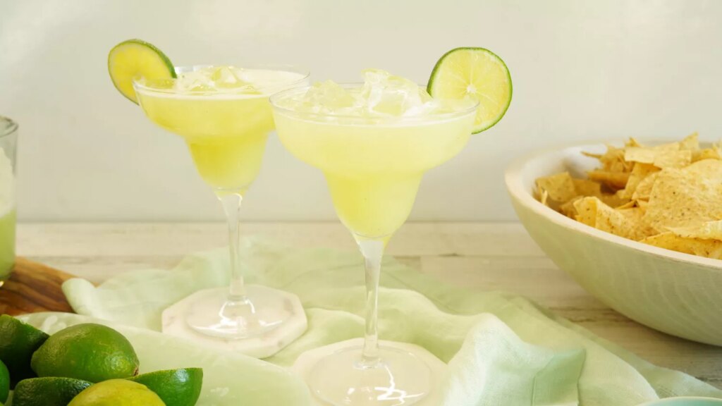 Two whole lime margaritas over ice with lime wedge garnishes