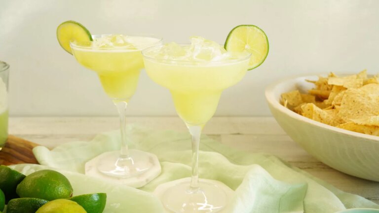 Two whole lime margaritas over ice with lime wedge garnishes
