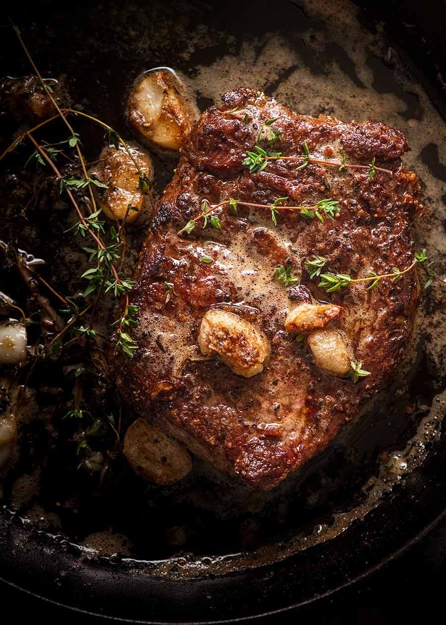 How to Cook Steak – like a chef! Recipe Medium rare steak in a black skillet with garlic thyme butter, fresh off the stove