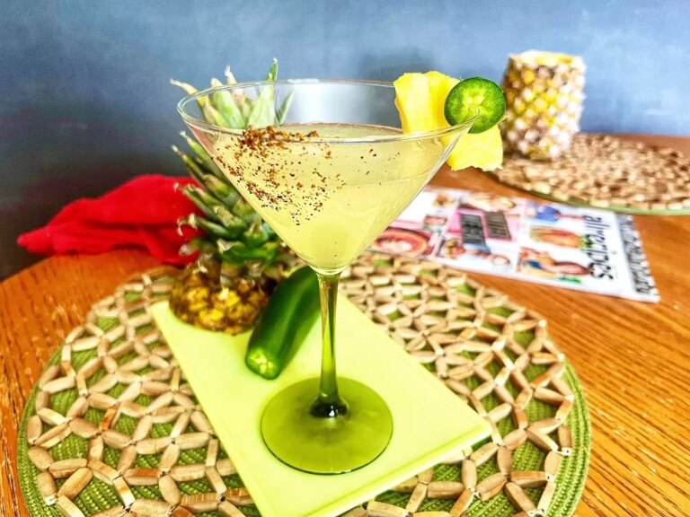 Pineapple jalapeno margarita garnished with tajin, jalapeno slice, and pineapple wedge
