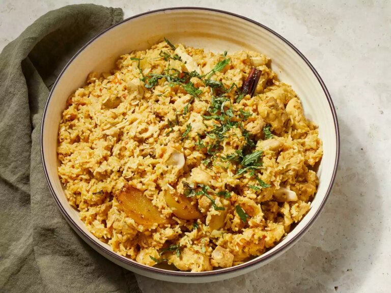 Close up on a bowl of chicken biryani, garnished with chopped mint leaves.