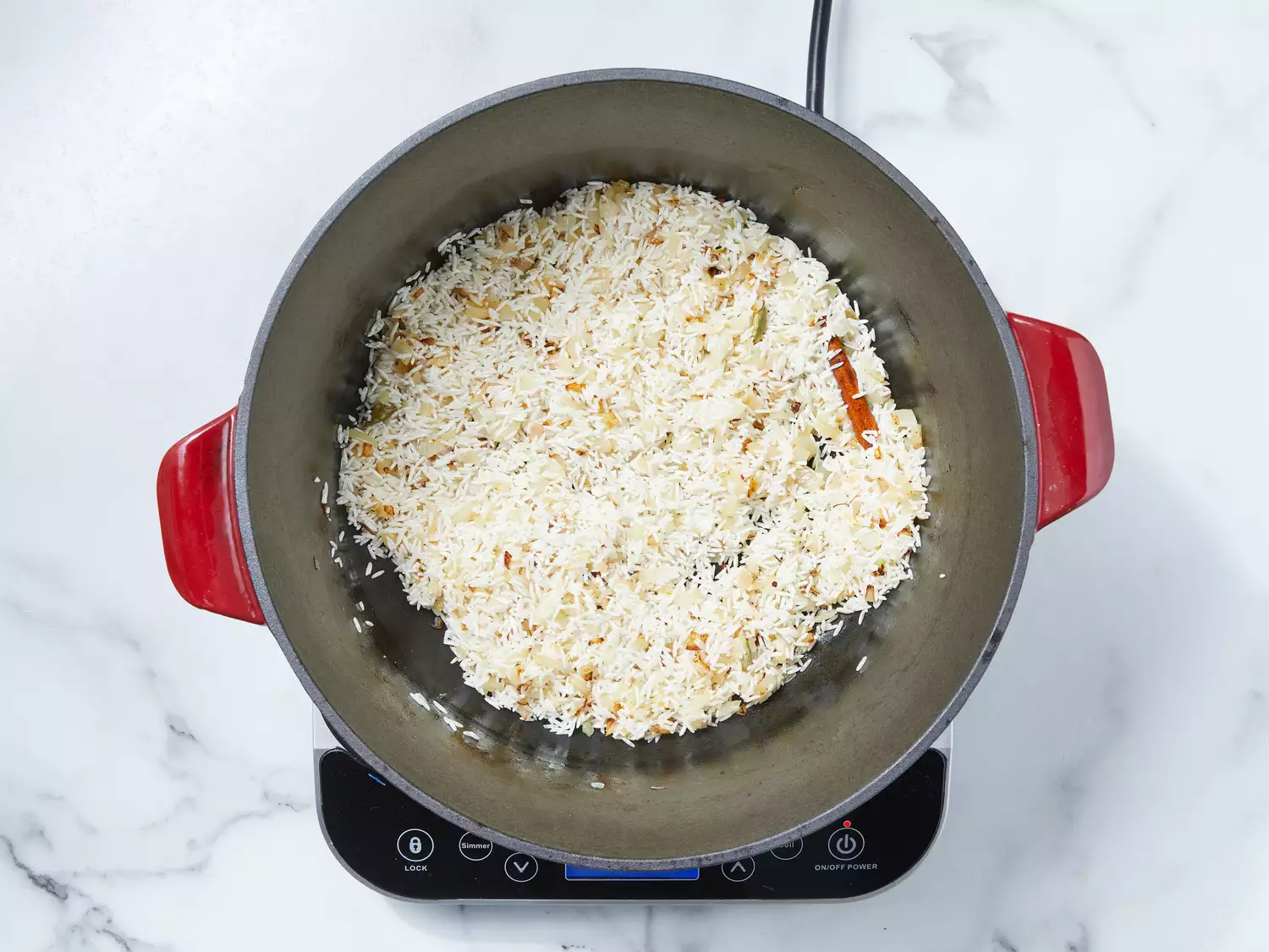 onions, cardamom pods, cloves, cinnamon stick, ground ginger and saffron mixed together with rice added, stirring until rice is coated with spices.