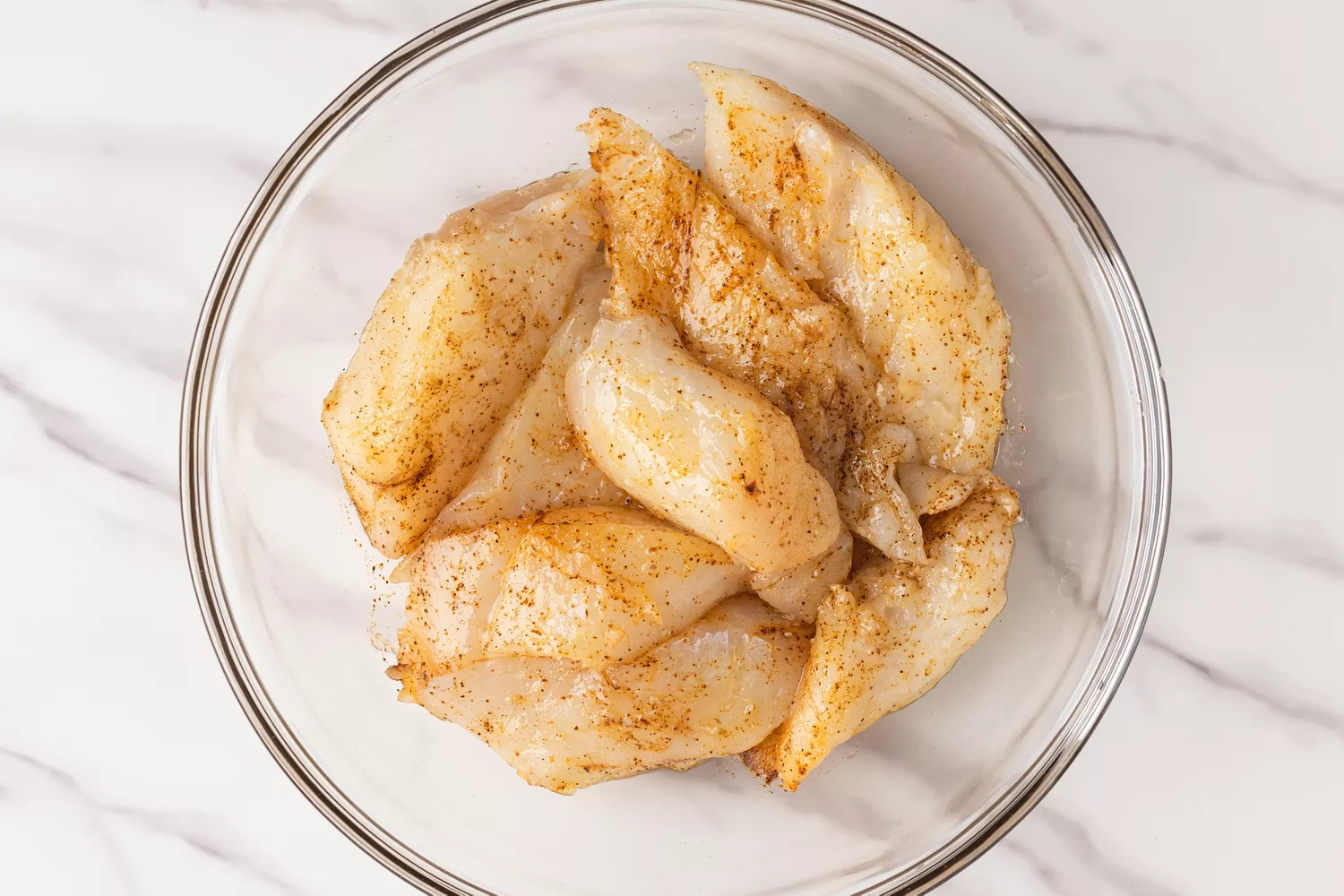 Seasoned fish pieces in a glass bowl. 